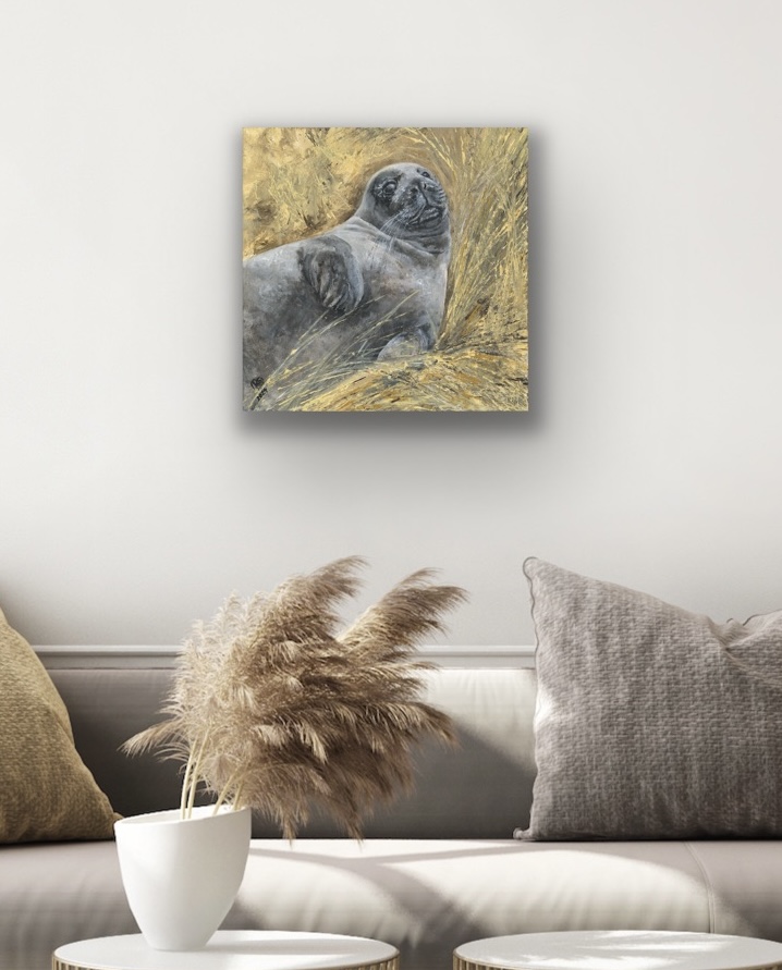 Held seal pup print styled above cushions with coastal tones and dried natural foliage